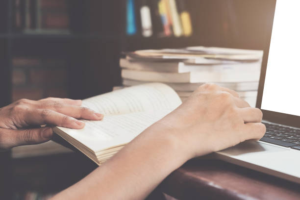 istock Closeup hand open book for reading, education or research at library, Education research concept with vintage tone 877349964