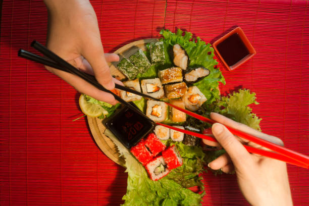 istock Japanese food restaurant platter set. Hand take roll. Set for two with chopsticks, ginger, soy, wasabi. Sushi at rustic wood background. 877356324