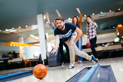 Happy friends having fun and enjoying playing bowling together