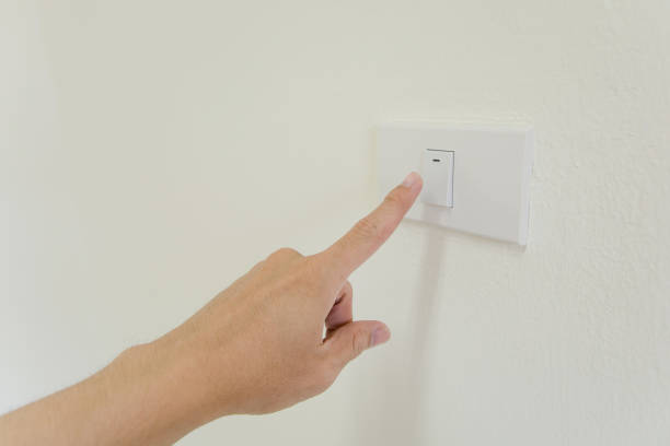 istock finger is turning on or off on light switch on walla. Copy space. 877365360