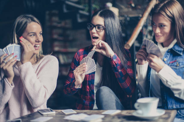 istock Three girls playing card in cafe. 877372552