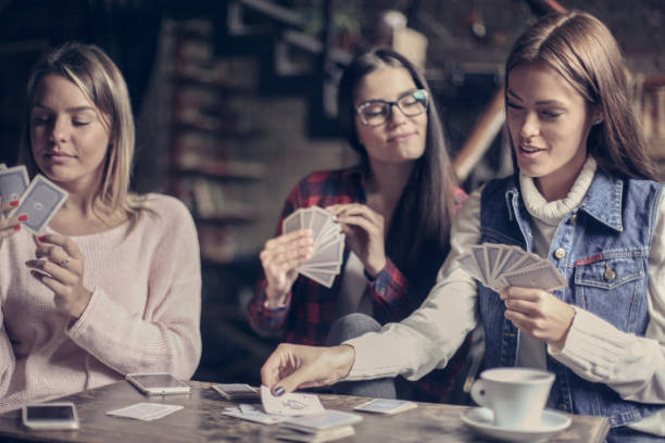 istock Three girls playing card in cafe. 877373414