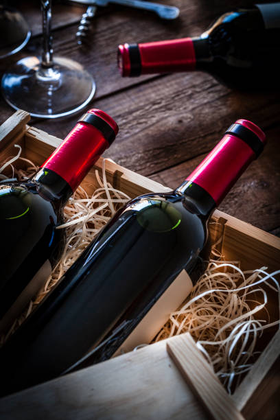 istock Red wine bottles packed in a wooden box shot rustic wooden table 877373468
