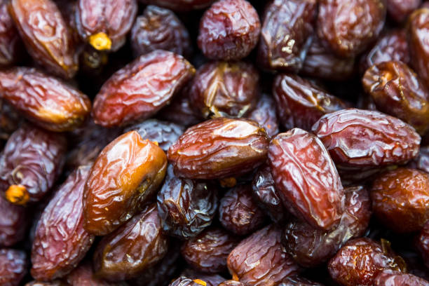 Heap of dried date fruits macro close up background Extreme macro close up image depicting a pile of dried dates for sale at the food market. Room for copy space. date fruit stock pictures, royalty-free photos & images