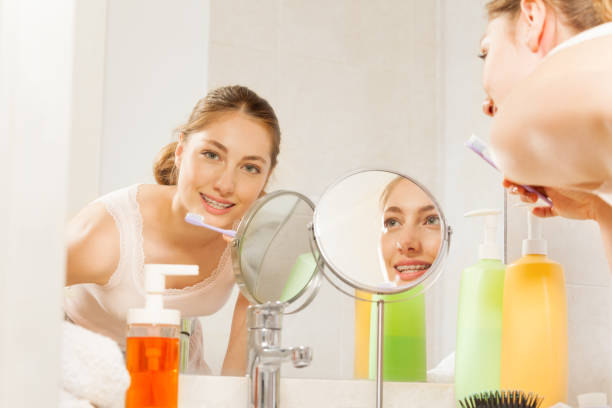 istock Woman brushing her teeth seen in bathroom mirror 877382708