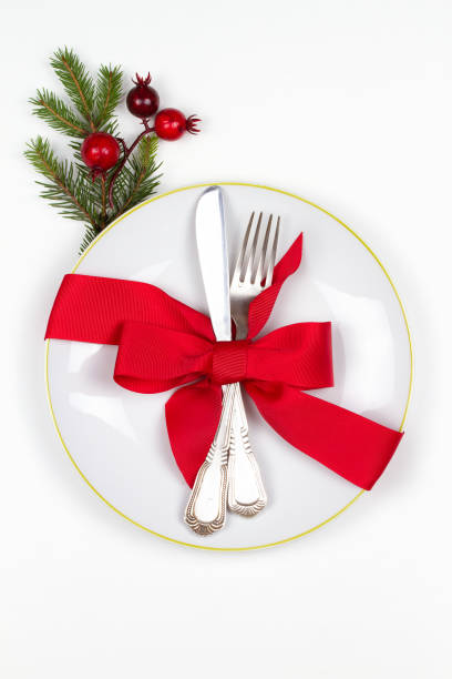 istock Christmas table place setting with plate, cutlery, pine branches,  ribbon and red berries. Winter holidays festive background 877384094