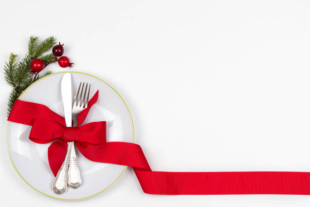 istock Christmas table place setting with plate, cutlery, pine branches,  ribbon and red berries. Winter holidays festive background 877384532