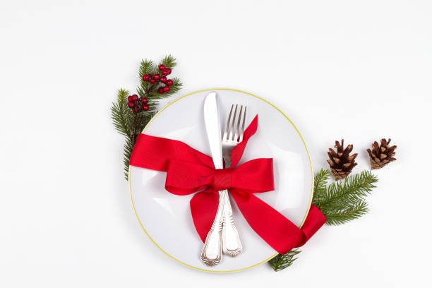 istock Christmas table place setting with plate, cutlery, pine branches,  ribbon and red berries. Winter holidays festive background 877384742