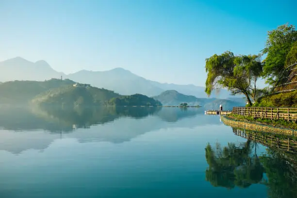 Photo of Reflection of trees, mountains, and islands on the clear water lake, sun moon lake.