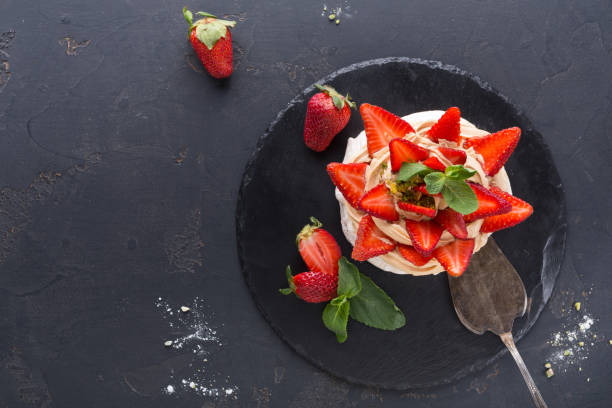 istock Anna Pavlova cake with strawberry on black background 877394840