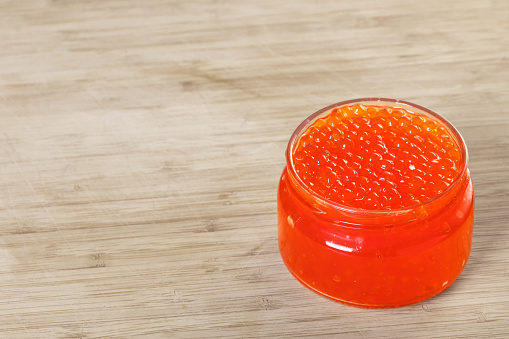 red caviar in a glass jar on wooden background