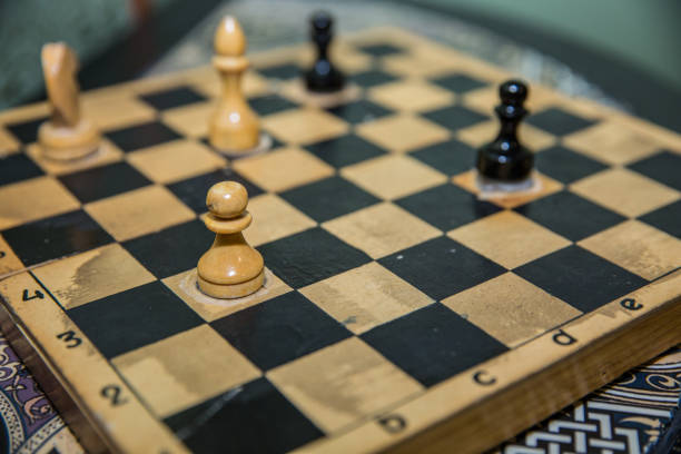 istock Vintage wooden chess pieces on an old chessboard. 877395062
