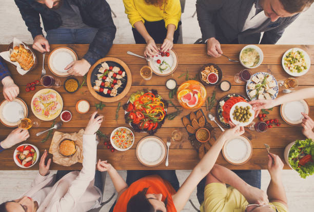 People eat and share healthy meals at served table dinner party
