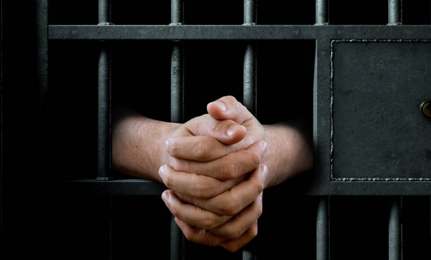 istock Jail Cell Door And Hands 877396442