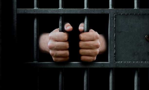 istock Jail Cell Door And Hands 877407576