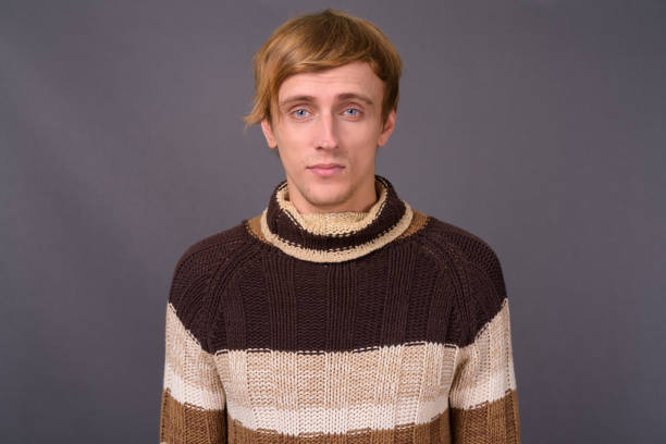 istock Young handsome man with bond hair against gray background 877442324