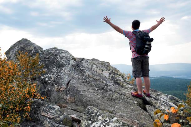 istock A man on a rock with a camera and a backpack in a mountain landscape. 877474614