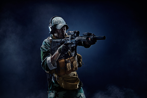 Special Forces soldier in action. Portrait of a Soldier. Soldier use special military equipment, weapons and tactical devices. The soldier is aiming.