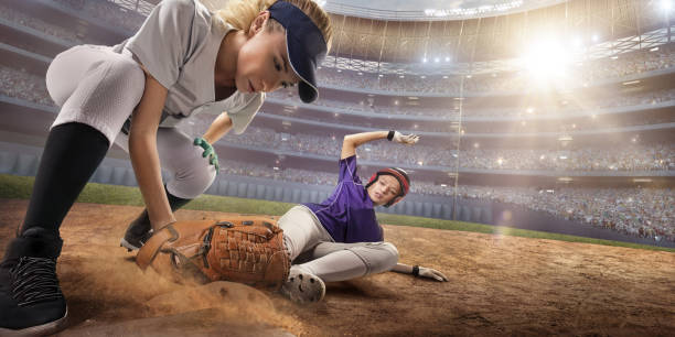 Softball female players on a professional arena. Baseball 3rd base slide Softball female players on a professional arena. Baseball 3rd base slide. Beautiful athlete in unbranded uniform on big arena. Softball player touches the base. The second player catches the ball. softball pitcher stock pictures, royalty-free photos & images