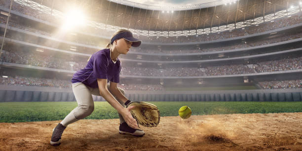 Softball female player on a professional arena Softball female player on a professional arena. Beautiful athlete in unbranded uniform on big arena. The player catches the ball. softball pitcher stock pictures, royalty-free photos & images