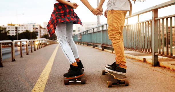 istock Young attractive couple riding skateboards and having fun 877493370