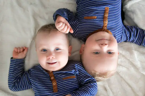 Identical twins lying upside down on white blanket