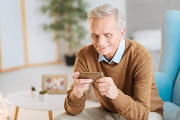 istock Beaming elderly man looking at photos on his smartphone 877501592