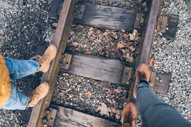 first person view down on the boots couple walk by railroad in autumn day