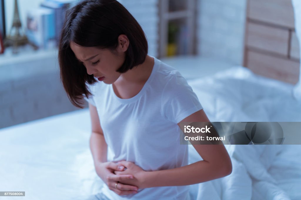 Asiatische Frauen, die ihren Bauch hart schmerzt wacht sie mitten in der Nacht während sie schläft. - Lizenzfrei Polyzystisches Ovar-Syndrom Stock-Foto