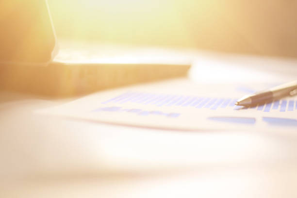 istock business background: laptop,financial chart and pen on office workplace 877516234