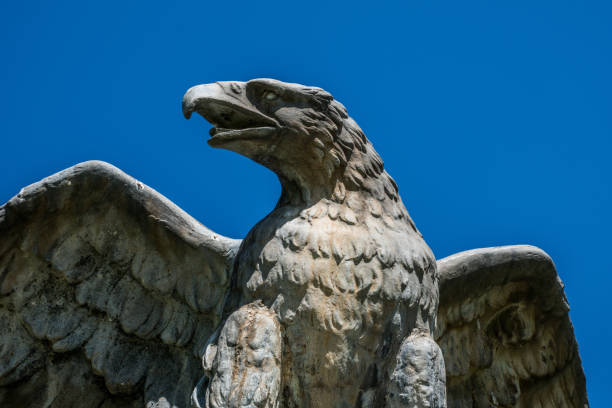 istock Eagle of stone against a clear blue sky 877592990