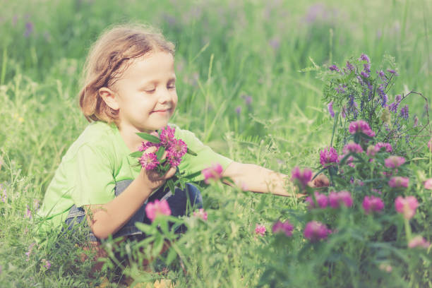 istock Cute little boy  playing with flowers in  park 877618582