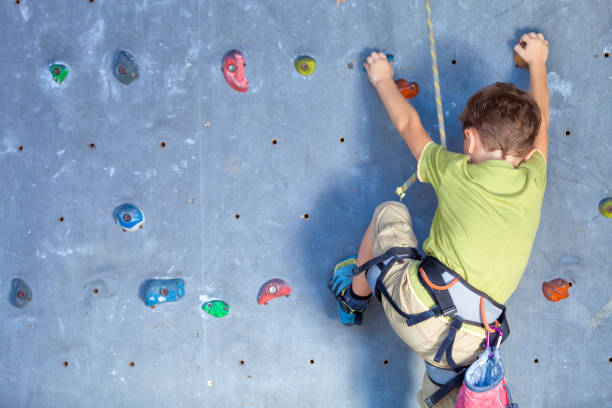 istock little boy climbing a rock wall 877619076