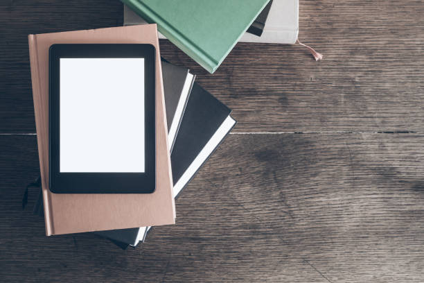 istock e-reader on stack of books on rustic wooden desk 877692102