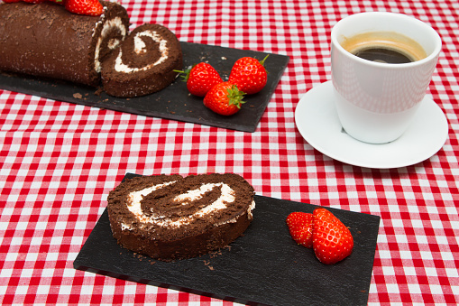 A chocolate swiss roll decorated with fresh strawberries