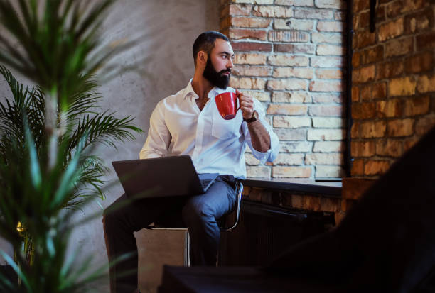 istock Urban bearded male drinks coffee and using a laptop. 877704522
