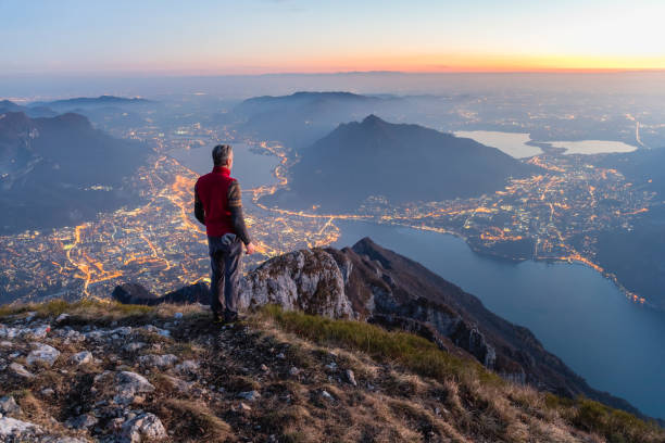 человек на вершине горы над городом - lake como water italy sunset стоковые фото и изображения