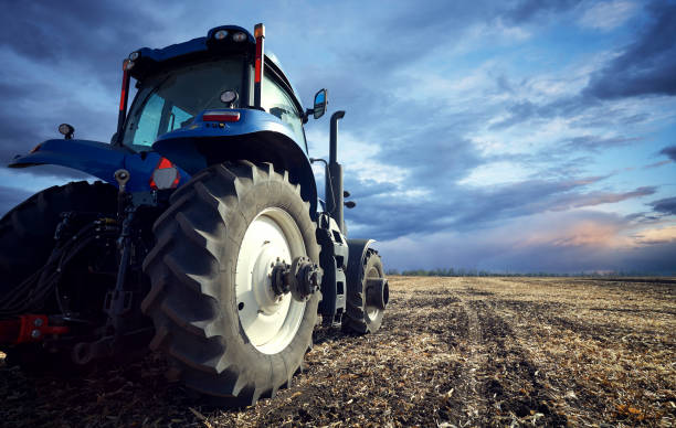 A powerful tractor handles the ground Tractor working on the farm, a modern agricultural transport, a farmer working in the field, tractor at sunset, fertile land, modern tractor closeup, cultivation of land agricultural machinery stock pictures, royalty-free photos & images