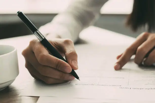 Photo of Closeup of Woman Completing Application Form