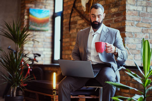 istock Urban bearded male drinks coffee and using a laptop. 877721494