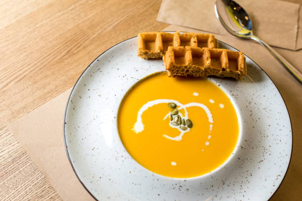 호박과 당근 수프 밝은 나무 배경에 벨기에 와플과 크림. 카페, 레스토랑 또는 가정 요리입니다. 건강 한 다이어트에 대 한 제조 법의 아이디어 - pumpkin soup soup cup pumpkin 뉴스 사진 이미지