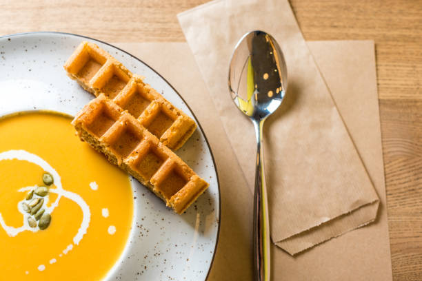 벨기에 함께 맛 있는 호박 크림 스프 조각 나무 테이블과 흰색 접시에 와플. 카페, 레스토랑 또는 가정 요리입니다. 건강 한 다이어트에 대 한 제조 법의 아이디어 - pumpkin soup soup cup pumpkin 뉴스 사진 이미지