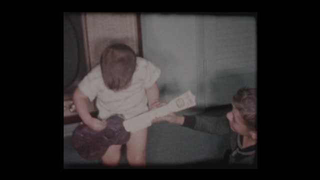 2 year old little boy plays toy guitar