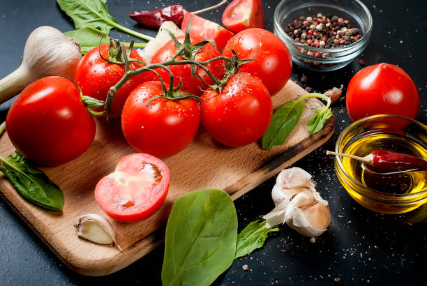 istock Black rustic tabletop with branch of tomatoes and herbs, top view 877753324
