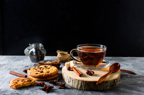 istock Cup of  tea, biscuits, cinnamon, anise on dark   background 877767920