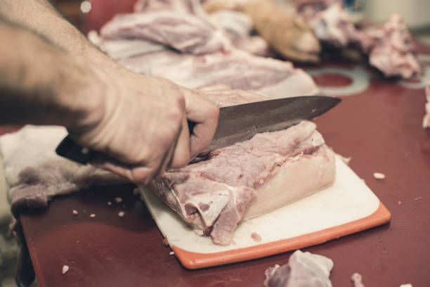 Man slicing pork meat on a table, working process closeup