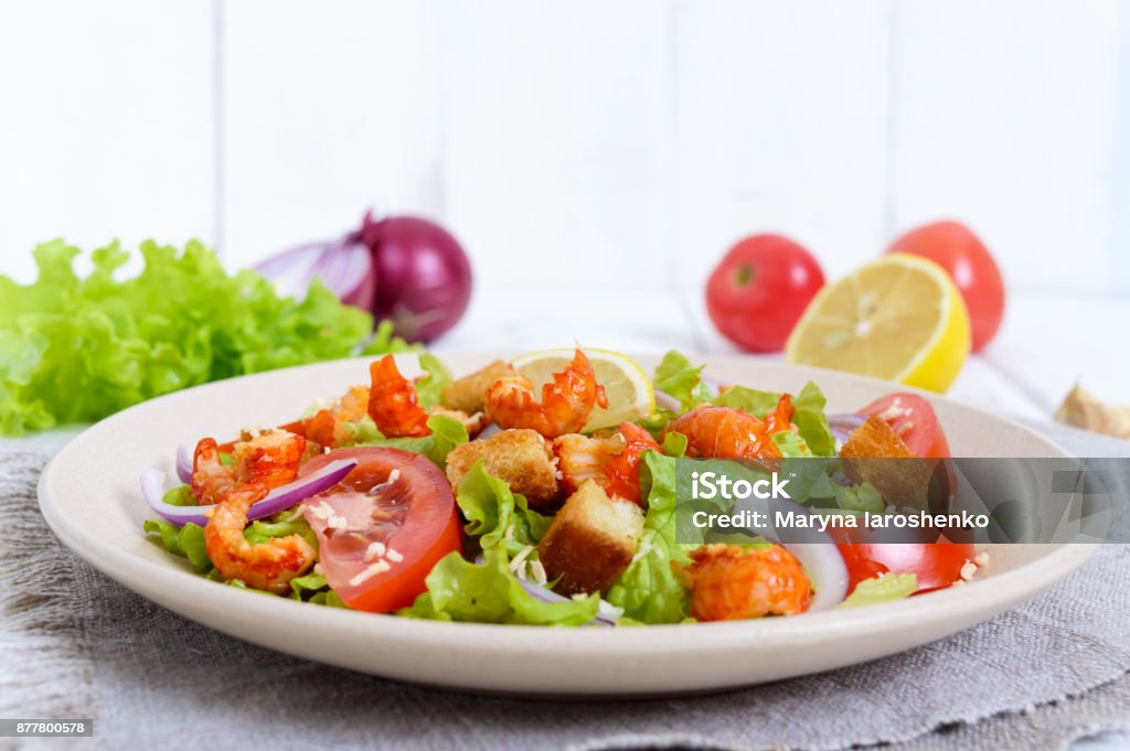 Light tasty salad with meat of a cancer, shrimps, lettuce, garlic croutons, tomatoes, red onions on a white background. Above Stock Photo