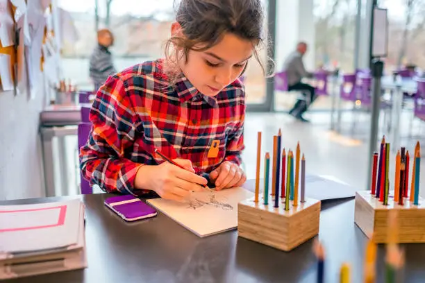 Photo of Cute schoolgirl drawing with pencils.