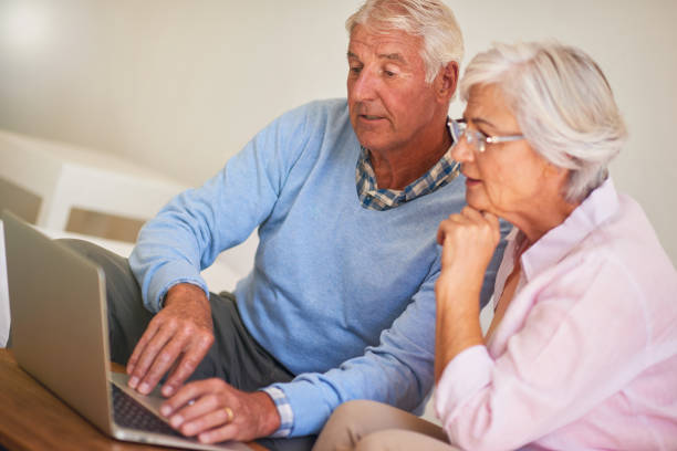istock Senior couple using laptop together at home 877834778