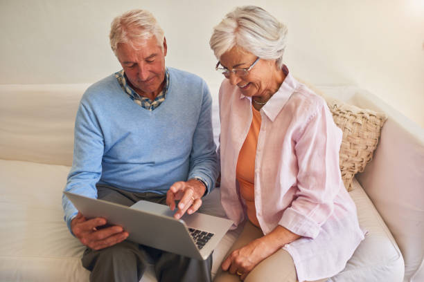 istock Senior couple using laptop together at home 877834816